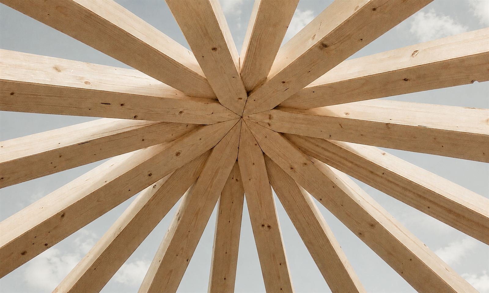 Sternförmige Holzbalken-Dachkonstruktion vor blauem Himmel